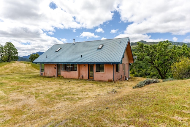 rear view of property with a mountain view and a lawn