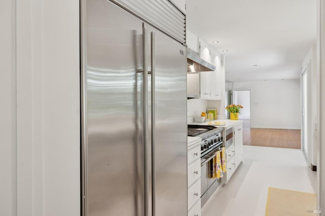 kitchen with high quality appliances, ventilation hood, and white cabinets