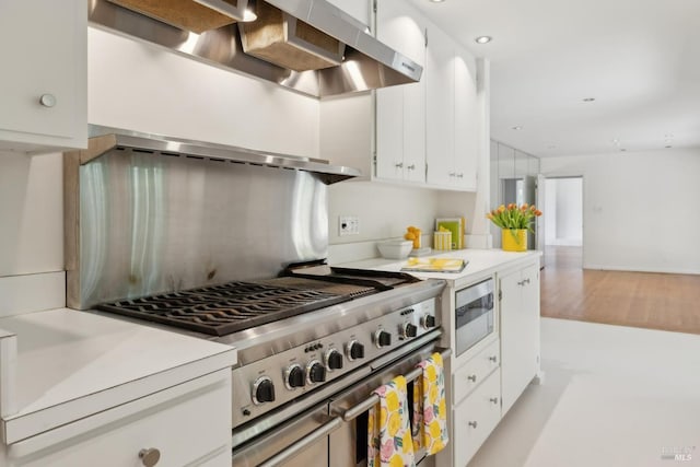 kitchen with stainless steel appliances, white cabinets, and range hood