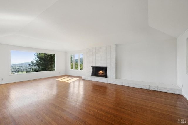 unfurnished living room featuring a brick fireplace, wood-type flooring, and vaulted ceiling