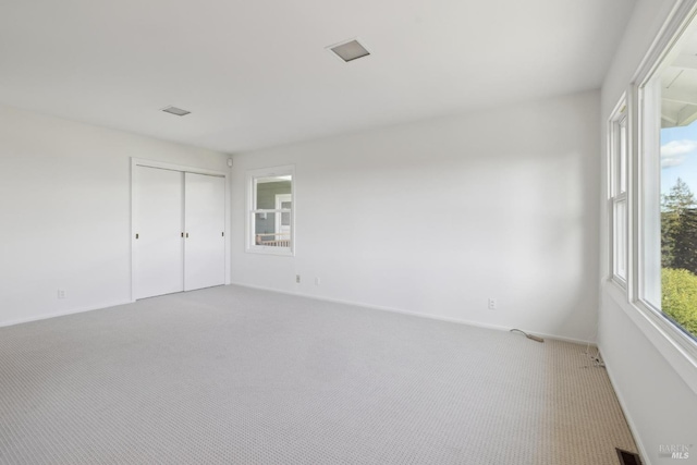 unfurnished bedroom featuring a closet, carpet flooring, and multiple windows