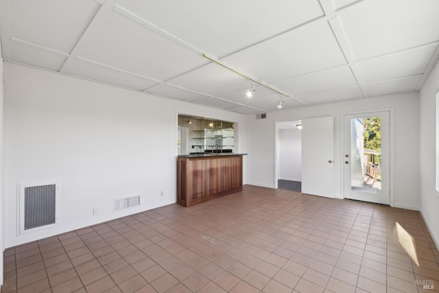 unfurnished living room with a drop ceiling and tile patterned floors