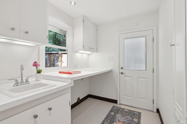 interior space with white cabinetry and sink