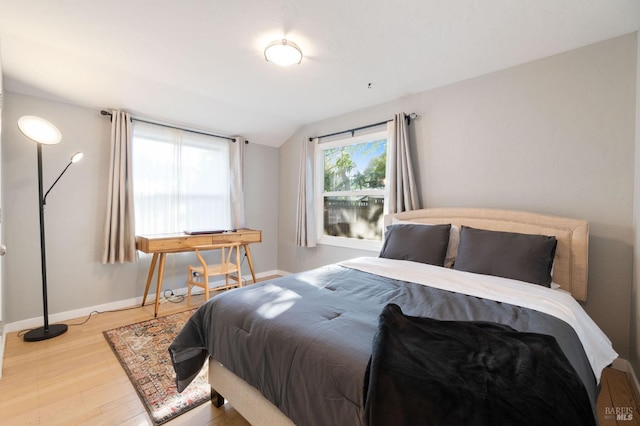 bedroom featuring baseboards, wood finished floors, and vaulted ceiling