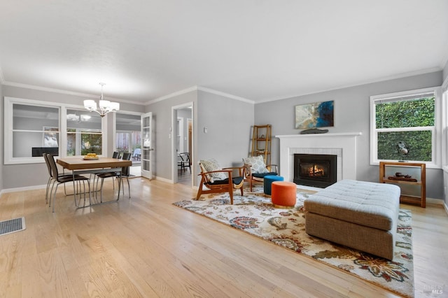 living area with visible vents, baseboards, light wood-style flooring, a tile fireplace, and a notable chandelier