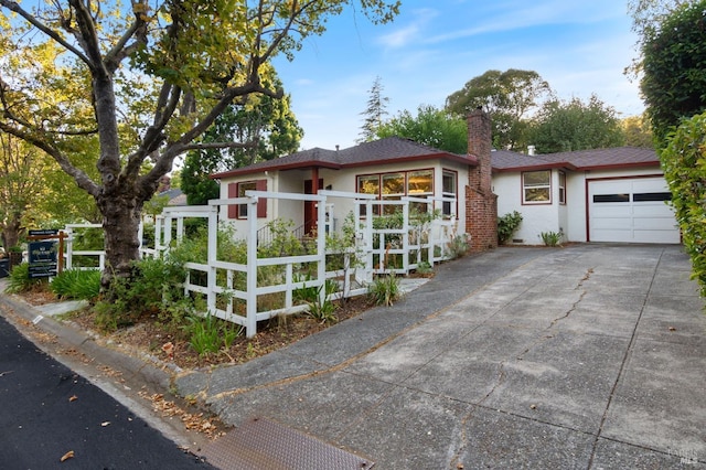 view of front of property with concrete driveway, a chimney, a fenced front yard, and stucco siding