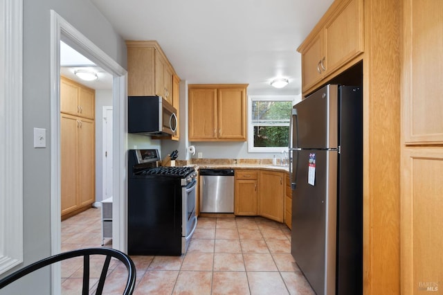 kitchen featuring light brown cabinets, light countertops, light tile patterned floors, stainless steel appliances, and a sink