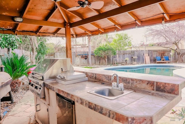 view of patio / terrace with an outdoor kitchen, a fenced backyard, area for grilling, a sink, and a fenced in pool