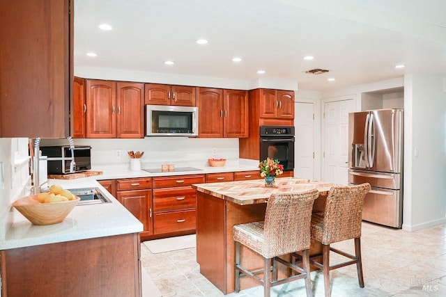 kitchen featuring a kitchen breakfast bar, light countertops, black appliances, and recessed lighting