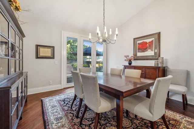 dining room featuring dark wood-type flooring, a chandelier, and vaulted ceiling