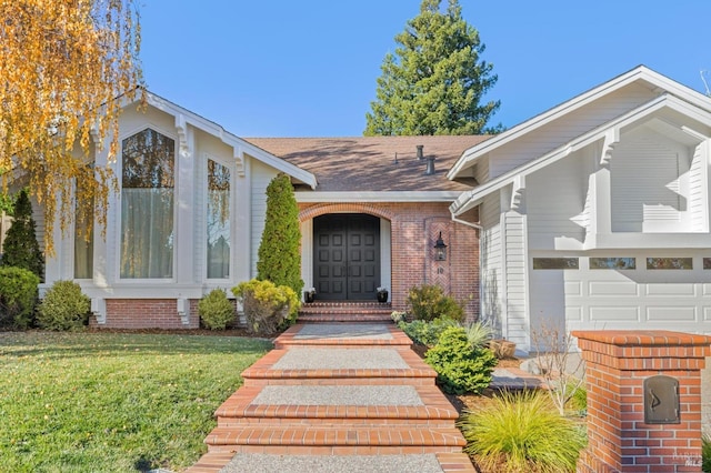 doorway to property with a garage and a lawn