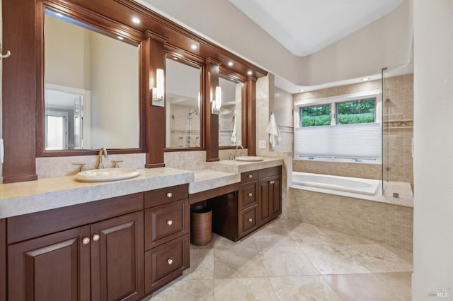 bathroom featuring a relaxing tiled tub, tile patterned floors, and vanity