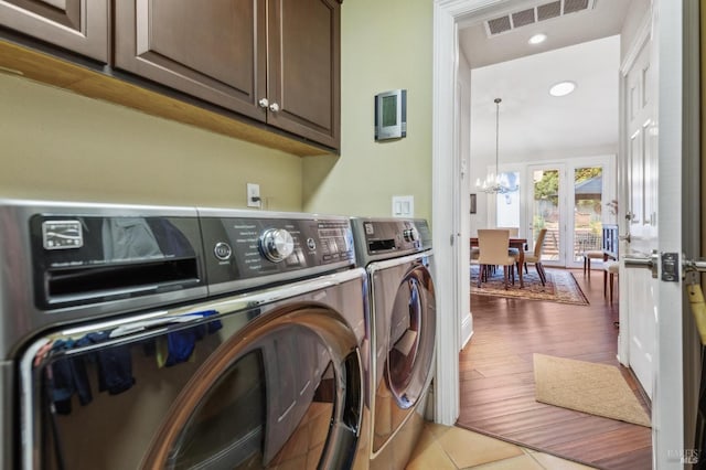 laundry room featuring an inviting chandelier, cabinets, light hardwood / wood-style floors, and washer and dryer