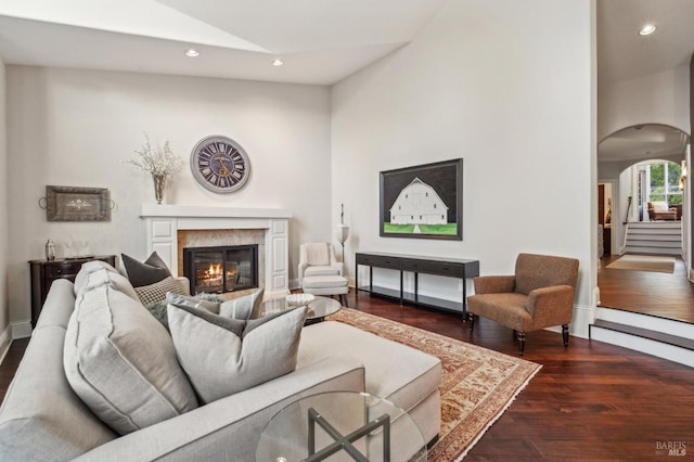 living room featuring lofted ceiling, a high end fireplace, and dark wood-type flooring