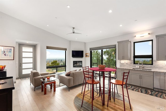 dining room featuring lofted ceiling, sink, a wealth of natural light, and light hardwood / wood-style floors