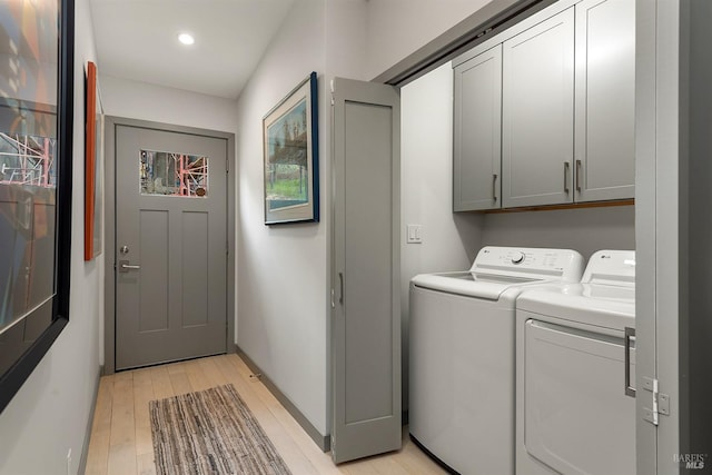 laundry area with cabinets, washer and clothes dryer, and light wood-type flooring