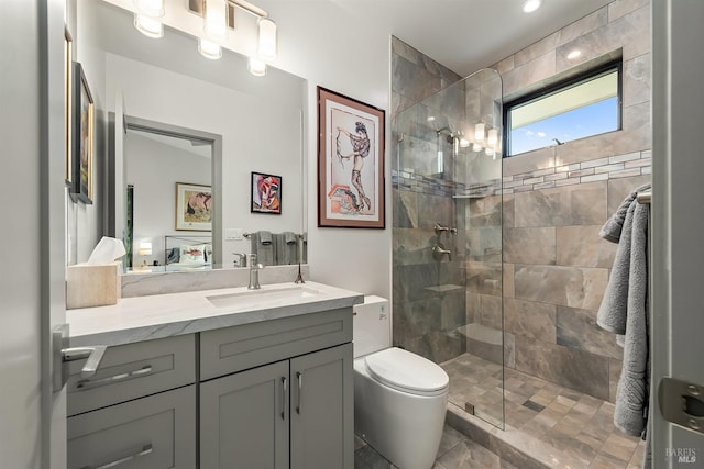 bathroom featuring tiled shower, vanity, and toilet