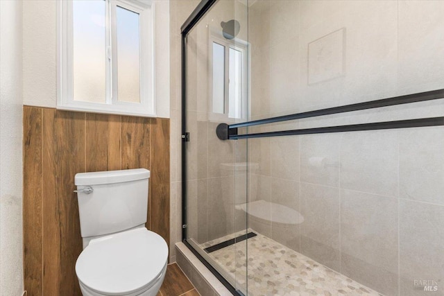 bathroom with a shower with door and toilet