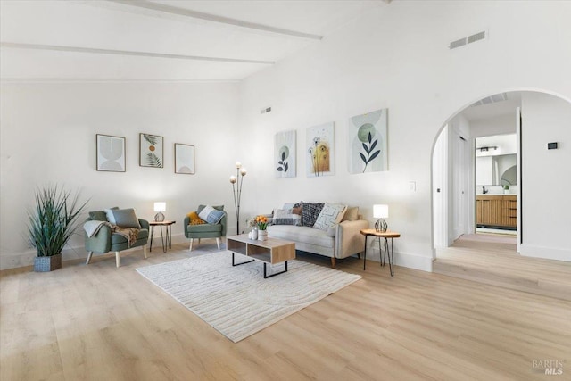 living room with beamed ceiling, high vaulted ceiling, and light hardwood / wood-style floors