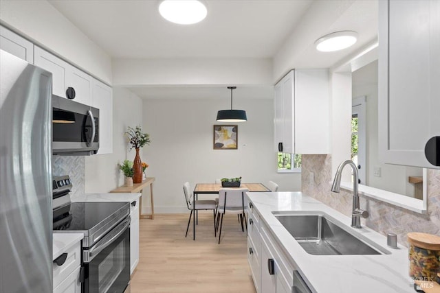 kitchen featuring sink, tasteful backsplash, light stone counters, appliances with stainless steel finishes, and white cabinets