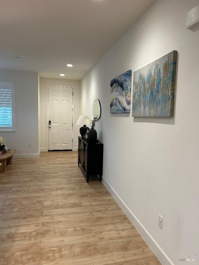 hallway with an AC wall unit and light wood-type flooring