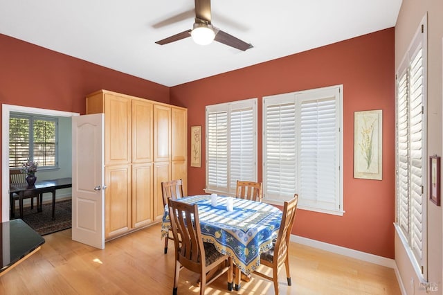 dining area with baseboards, a ceiling fan, and light wood finished floors