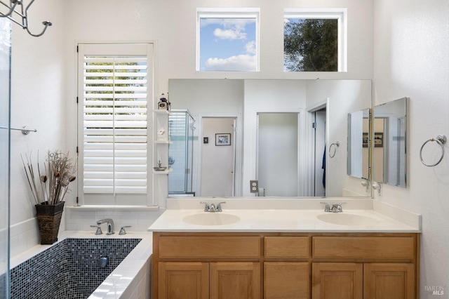 full bath featuring double vanity, a washtub, a stall shower, and a sink