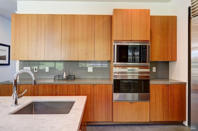 kitchen with light stone counters, appliances with stainless steel finishes, sink, and tasteful backsplash