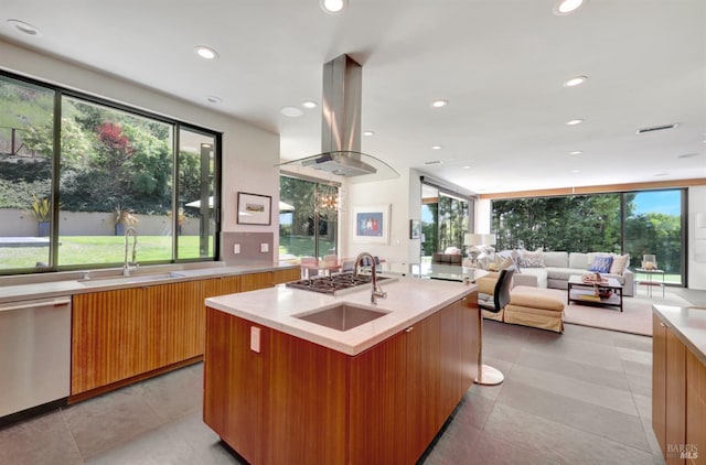 kitchen with sink, island range hood, appliances with stainless steel finishes, plenty of natural light, and an island with sink