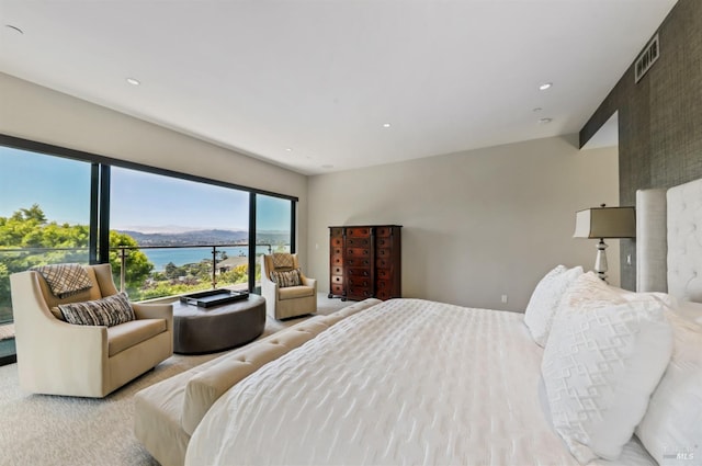 bedroom featuring a water view and light carpet