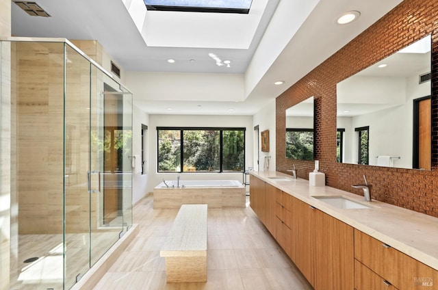 bathroom featuring vanity, shower with separate bathtub, a skylight, and backsplash