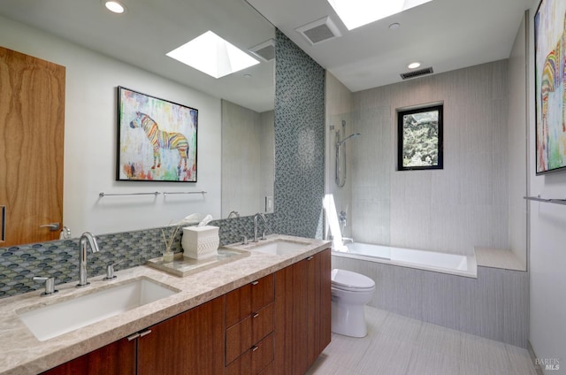 full bathroom with tile patterned floors, toilet, a skylight, vanity, and tiled shower / bath combo