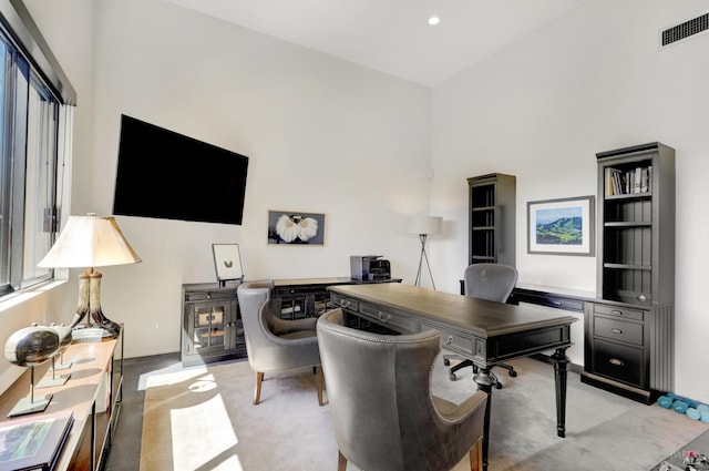 carpeted home office featuring a high ceiling