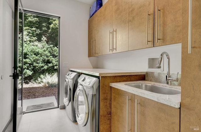 washroom with sink, cabinets, washing machine and clothes dryer, and light tile patterned flooring