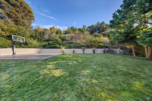 view of yard with basketball hoop and fence