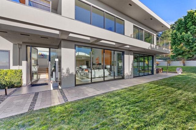 rear view of property featuring a lawn and stucco siding