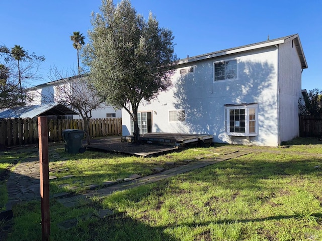 back of house featuring a wooden deck and a yard