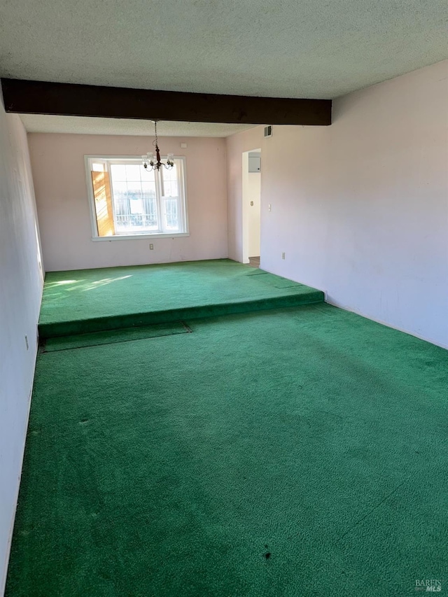 spare room featuring an inviting chandelier, beamed ceiling, a textured ceiling, and carpet