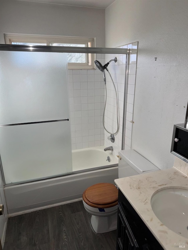 full bathroom with vanity, hardwood / wood-style floors, shower / bath combination with glass door, and toilet