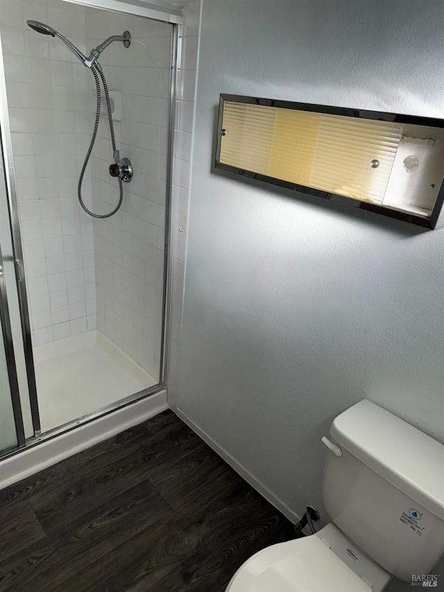 bathroom featuring wood-type flooring, toilet, and an enclosed shower