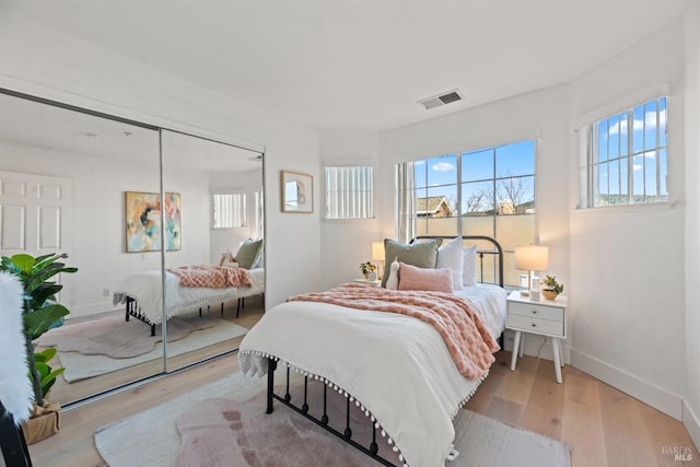 bedroom with multiple windows, light hardwood / wood-style floors, and a closet