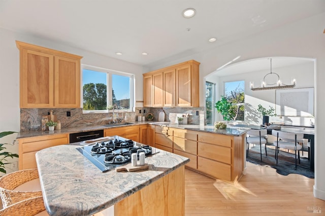 kitchen with light stone counters, sink, stainless steel gas stovetop, and light brown cabinets