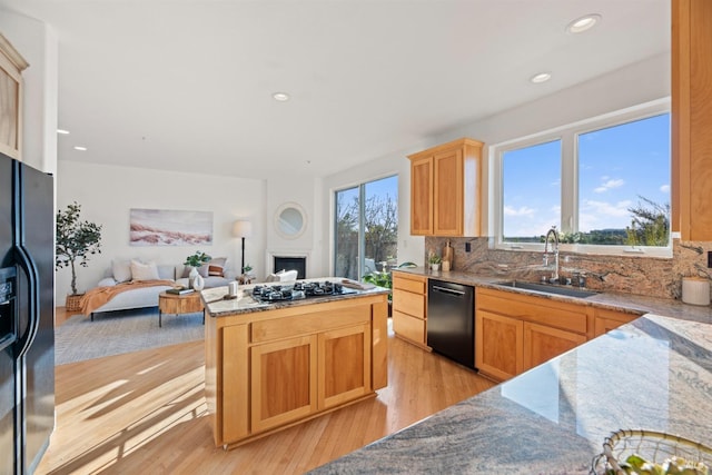 kitchen featuring sink, backsplash, light hardwood / wood-style flooring, and black appliances