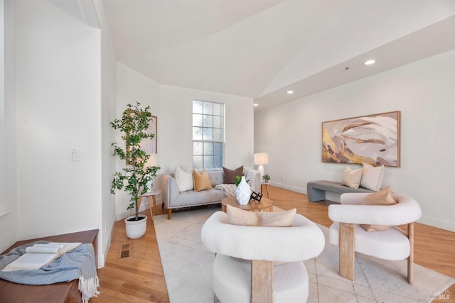 living room featuring lofted ceiling and light hardwood / wood-style floors