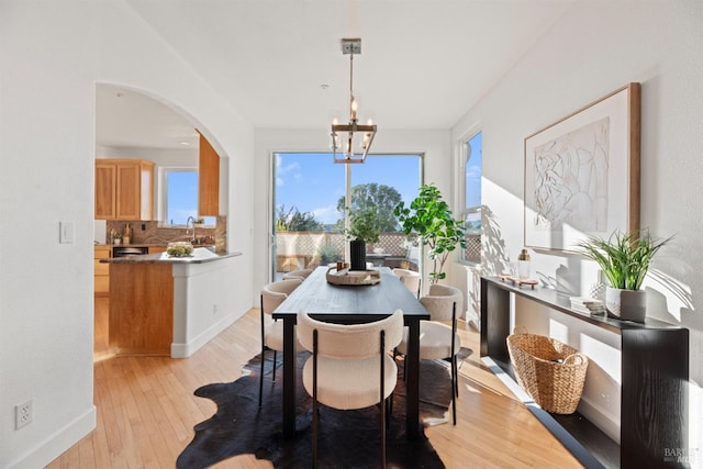 dining space featuring an inviting chandelier, sink, and light wood-type flooring