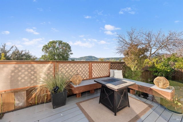 wooden deck featuring an outdoor fire pit and a mountain view