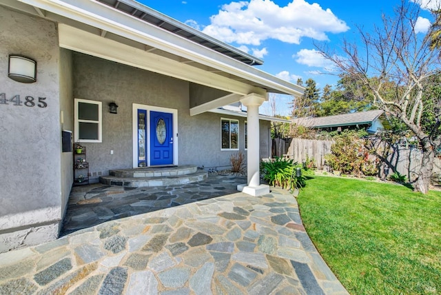 view of exterior entry featuring a lawn