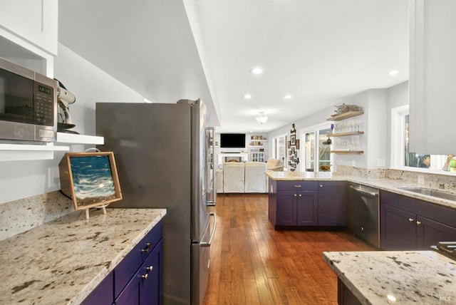 kitchen featuring sink, dark hardwood / wood-style floors, kitchen peninsula, stainless steel appliances, and light stone countertops