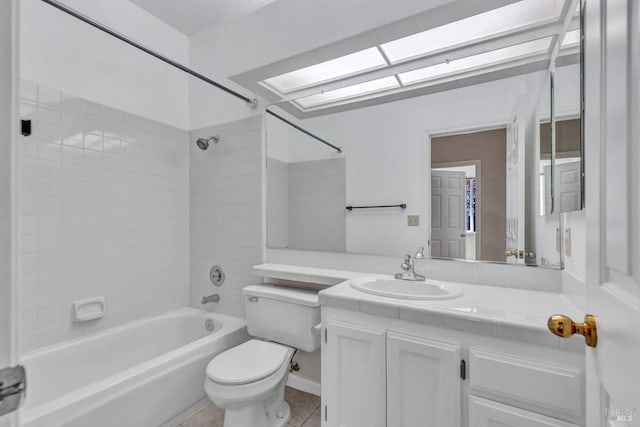 full bathroom with tile patterned flooring, a skylight, vanity, toilet, and tiled shower / bath