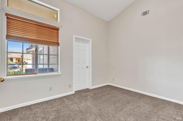 carpeted empty room featuring lofted ceiling